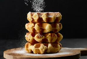 A stack of baked Belgian waffles sprinkled with powdered sugar photo