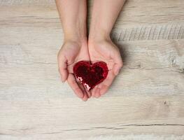 Female hands holding a red heart, concept of donation, kindness photo