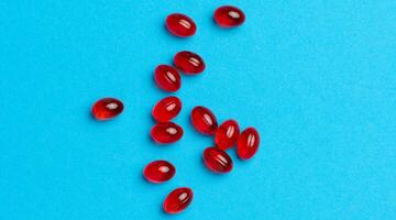 Orange capsules with fish oil on a blue background, top view photo