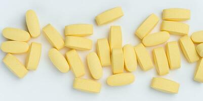 Yellow oval tablets on a white background, top view photo