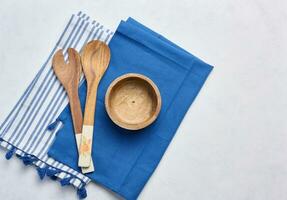 Empty bowl and wooden spoons on a white table, top view photo