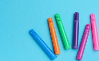 Multicolored felt-tip pens on a blue background, top view photo