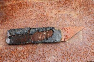 Old rusty homemade metal knife on an iron surface. Horizontal photo