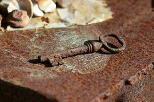 Rusty metal rustic old key on an iron surface - close-up, horizontal photo. photo