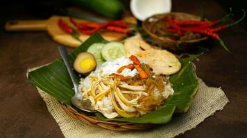 Nasi liwet is a Indonesian traditional food cooked with coconut milk, chicken broth, lemongrass and spices so that it has a savory taste and distinctive aroma. Cucumber and crackers are complementary. photo