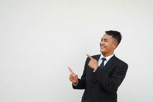 Portrait Young handsome Asian businessman with happy and smiling face finger pointing at copy space isolated on white background photo