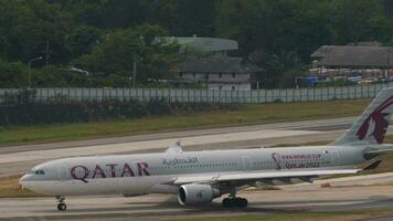 PHUKET, THAILAND FEBRUARY 13, 2023 - Airbus A330 of Qatar Airways taxiing at Phuket Airport, side view. Passenger aircraft on the runway. Tourism and travel concept video