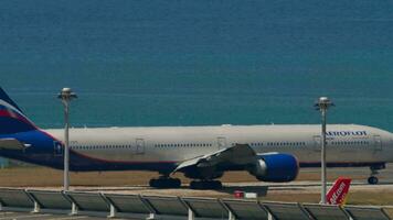 phuket, Tailandia febrero 20, 2023 boeing 777, real academia de bellas artes 73135 de aeroflot rodaje en el pista a phuket aeropuerto. lado ver de avión a calle de rodaje azul mar antecedentes. aeropuerto en isla video