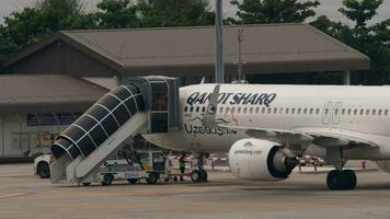 Phuket, Thailand Februar 25, 2023 - - Flugzeug Airbus a321 von qanot Sharq beim Phuket Flughafen. Verkehrsflugzeug Preflight Service. Treppe angedockt zu Flugzeug. Flugzeug mit Treppe beim das Terminal. video