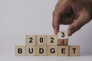 2024 Budget planning and allocation concept. Hand flips wooden cube and changes the inscription BUDGET 2023 to BUDGET 2024 on white background, Copy space. Use for banner and presentation. photo