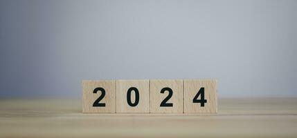 From 2023 to 2024. Merry Christmas and Happy New Year, numbers on wooden cube blocks on wooden table with copy space. 2024 new year idea concept. photo