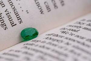 Emerald gemstone on opened book photo