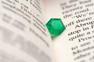 Emerald gemstone on opened book photo