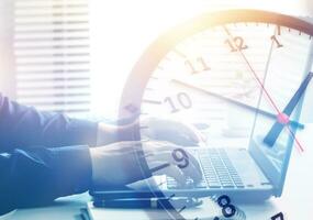 Working hours and working overtime. Close-up view of an employee typing on a computer with a clock overlapping. concept of effective time management and scheduling of company work hours. photo