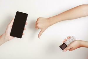 A hand holds a push-button telephone and shows a bad sign towards the smartphone photo