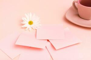 el concepto es rosado. un taza de café, hojas para escribiendo, un bolígrafo y un crisantemo en un rosado antecedentes. foto