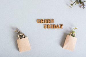 Green Friday inscription and paper bags with branches on green background top view photo