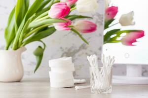 Personal hygiene, cleanliness and skin care. Cotton pads and swabs on the table in front of the mirror. photo