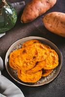 Homemade sliced baked sweet potato on a plate on the table vertical view photo