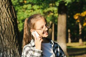 Cheerful girl in glasses talking on a dump phone outside photo