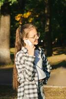 Cheerful girl in glasses talking on a dump phone outside vertical view photo