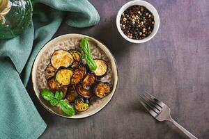 Appetizing fried eggplant with spices and herbs on a plate on the table top view photo