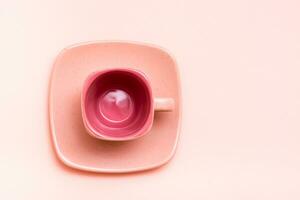 Pink concept. Empty square coffee cup on a saucer on a pink background. Top view photo