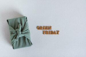 Green friday gift furoshik and inscription on green background top view photo