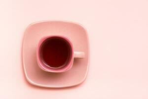 Pink concept. Square coffee cup with a pink drink on a saucer on a pink background. Top view photo