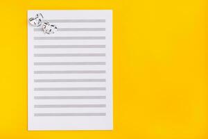 Blank sheet music and hearts cut from music text on yellow background. Top view. Copy space photo