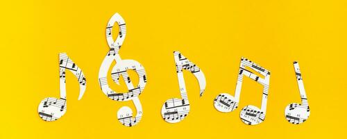 musical notas y clave cortar desde papel con musical texto en un fila en amarillo antecedentes. web bandera foto