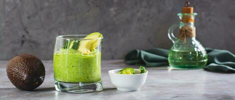 Green smoothie from avocado and cucumbers in a glass on the table web banner photo