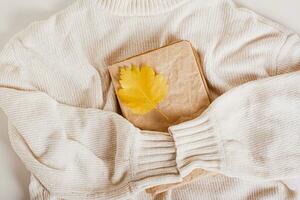 Cozy autumn old book and autumn leaf on a knitted sweater top view photo