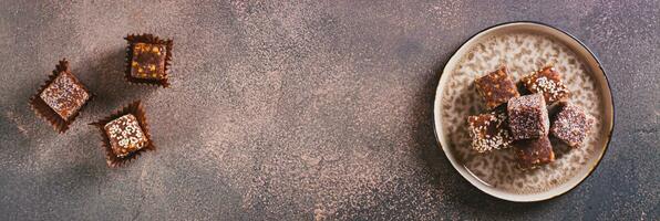 Sugar free candies made from fruit paste, nuts and sesame seeds on a plate top view web banner photo