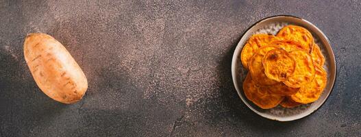 Homemade sliced baked sweet potato on a plate on the table top view web banner photo