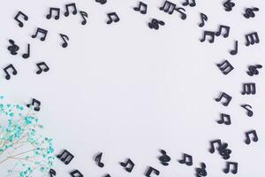 Musical concept frame made of black notes and dried flowers on a light background photo