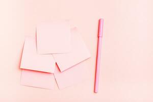 el concepto es rosado. blanco cuadrado pequeño hojas de papel y un bolígrafo en un rosado antecedentes. parte superior ver foto