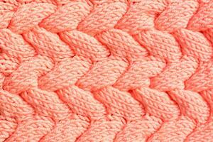 Textured background. Knitted fabric in peach color in the form of intertwined braids. Top view photo