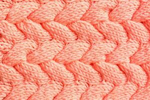 Textured background. Knitted fabric in peach color in the form of intertwined braids. Top view photo