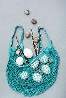 Happy Easter. Chicken and quail eggs falling into a blue mesh bag with pussy willow branches on a gray background photo
