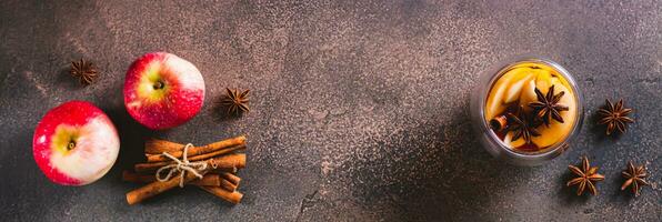Apple tea with cinnamon, honey and anise in a cup and teapot on the table top view web banner photo