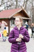 A cute girl in glasses holds a bottle with water bought in a food truck in a city park. Takeaway food photo