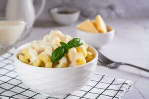 apetitoso pasta con queso salsa y albahaca en un cuenco en el mesa foto