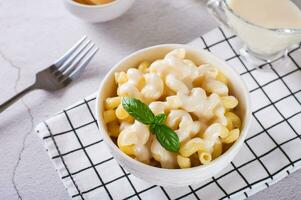 American pasta in a cheese sauce with basil leaves in a bowl photo