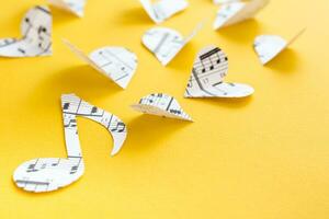 Musical notes, clef and hearts cut from paper with musical text on yellow background photo