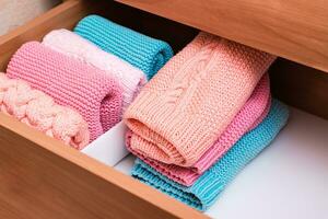 Organization and order. A stack of knitted clothes next to a box of neatly folded items in a dresser drawer photo