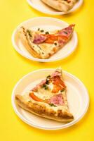 para llevar y entrega. Tres piezas de Pizza en desechable el plastico platos en un amarillo antecedentes. almuerzo para un grupo de amigos. vertical ver foto
