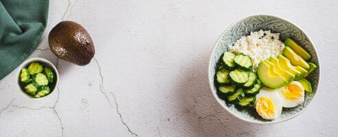 Fresh cottage cheese, avocado, cucumber and boiled egg in a plate top view web banner photo