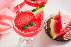 Watermelon lemonade with watermelon pieces in glasses on pink background photo