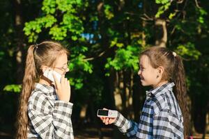 One girl gives another dump phone in a summer sunny park photo